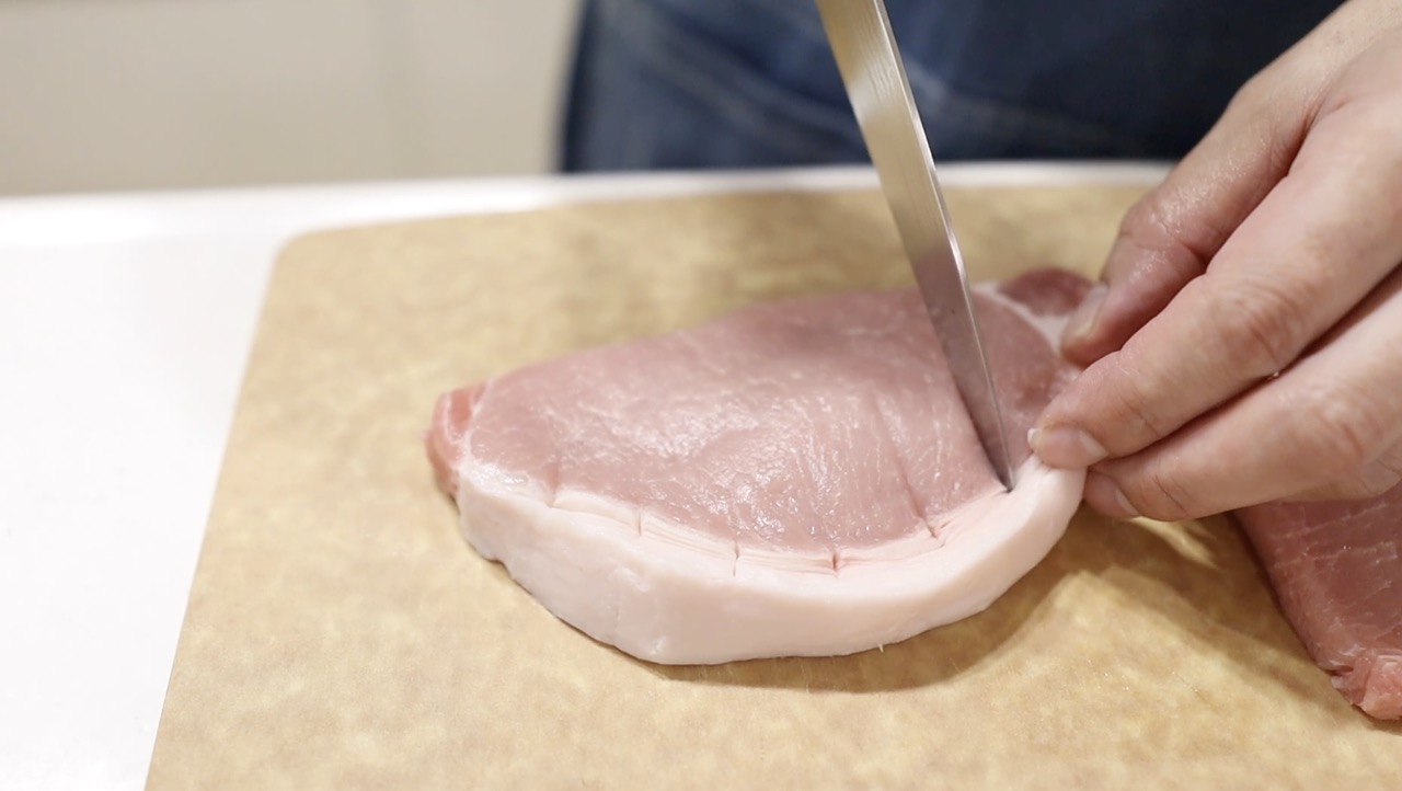 豚ロースの脂と赤身の境目に切れ目を入れる