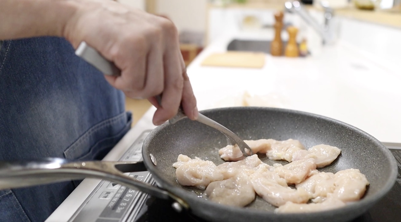 片栗粉をまぶした鶏むね肉をフライパンで焼く